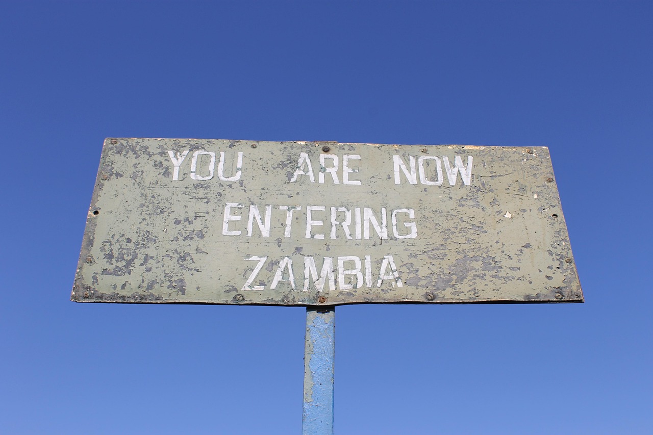Faded metal sign in front of the sky that reads 